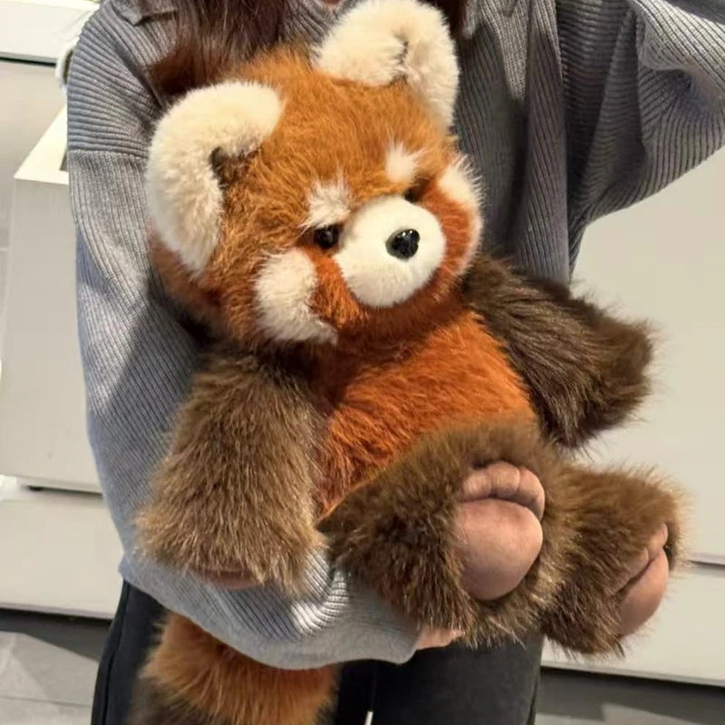 Person holding a plush toy red panda in an indoor setting