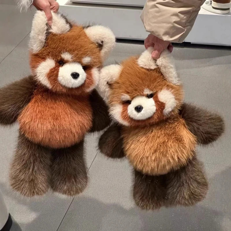 Two plush red panda toys held by hands on a light gray floor.